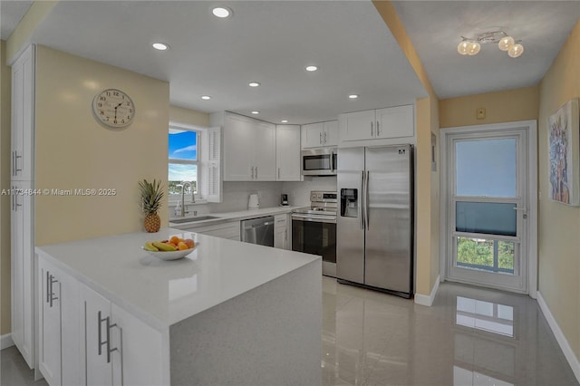 kitchen featuring appliances with stainless steel finishes, kitchen peninsula, sink, and white cabinets