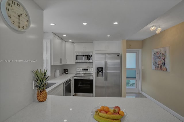 kitchen with stainless steel appliances, white cabinetry, and light stone counters