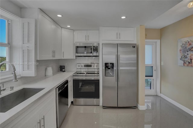 kitchen with sink, white cabinetry, light tile patterned floors, stainless steel appliances, and decorative backsplash