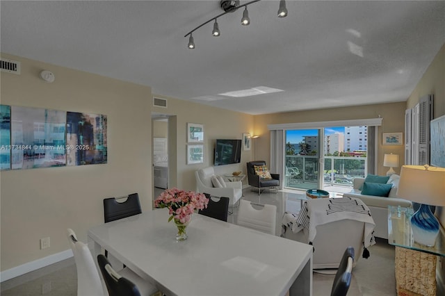 dining area featuring track lighting and a textured ceiling