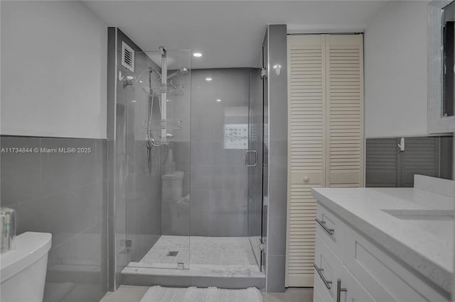 bathroom featuring vanity, tile walls, toilet, and walk in shower