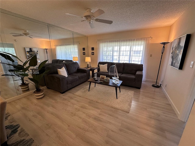 living room featuring ceiling fan, light hardwood / wood-style flooring, and a textured ceiling