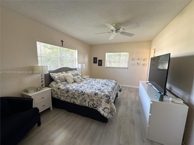 bedroom with ceiling fan, a textured ceiling, and light hardwood / wood-style flooring