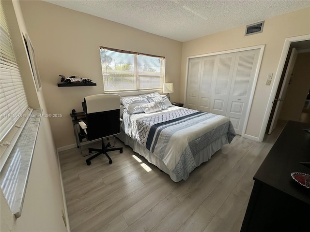 bedroom featuring a closet, light hardwood / wood-style flooring, and a textured ceiling