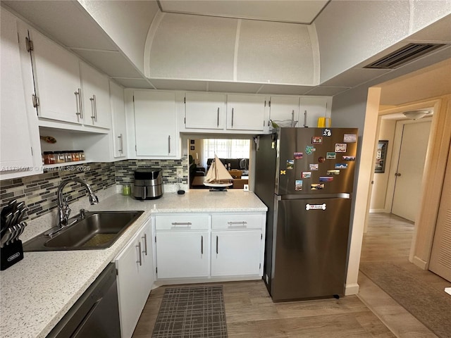 kitchen with sink, stainless steel refrigerator, dishwasher, white cabinetry, and decorative backsplash