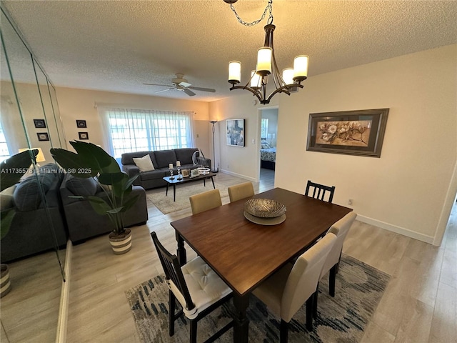 dining space with ceiling fan with notable chandelier, a textured ceiling, and light wood-type flooring