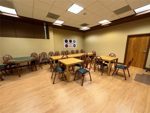 dining room with a drop ceiling and light hardwood / wood-style flooring