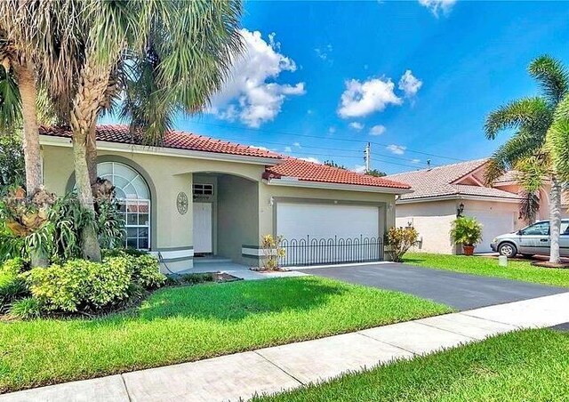 mediterranean / spanish-style house featuring a garage and a front yard