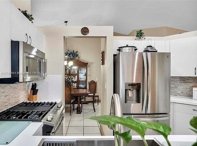 kitchen featuring stainless steel appliances, light tile patterned floors, decorative backsplash, and white cabinets