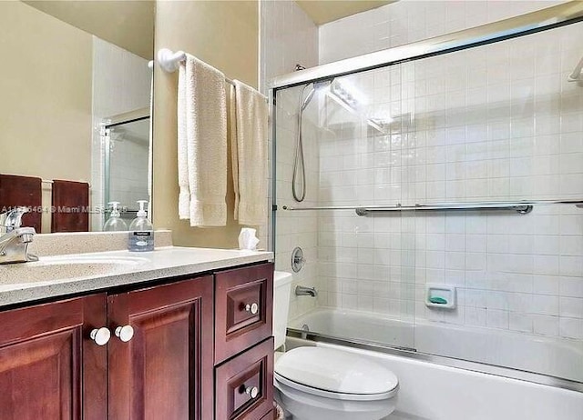 full bathroom with enclosed tub / shower combo, vanity, and toilet