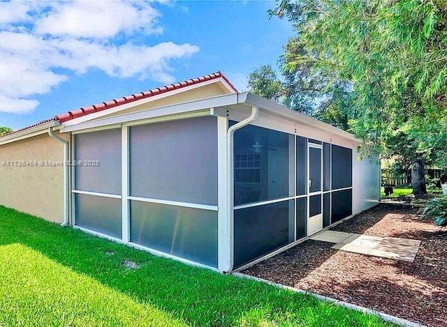 view of side of property with a sunroom and a yard