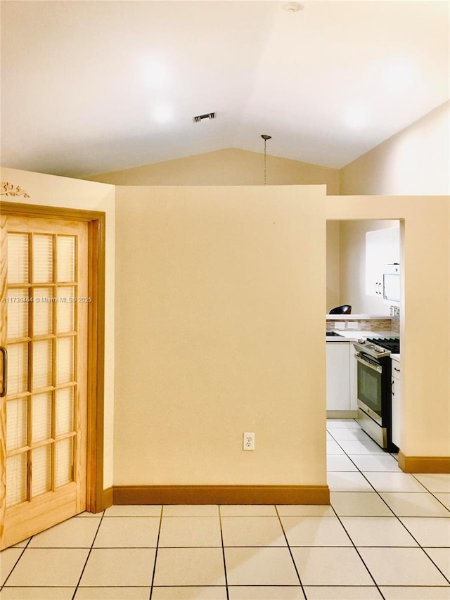 spare room with lofted ceiling and light tile patterned floors