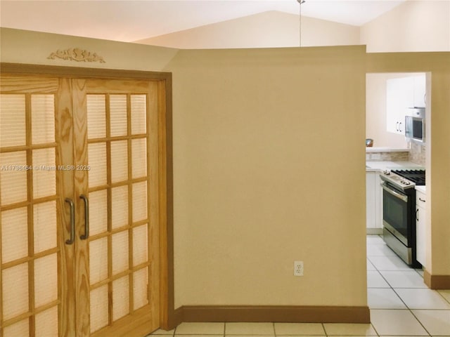 interior space featuring stainless steel gas range oven, lofted ceiling, and light tile patterned floors