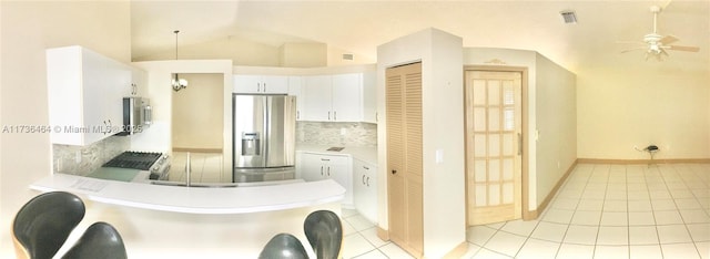 kitchen featuring stainless steel refrigerator with ice dispenser, light tile patterned flooring, range, vaulted ceiling, and white cabinets