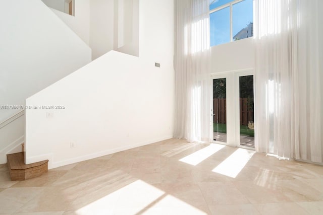 tiled spare room featuring french doors and a high ceiling