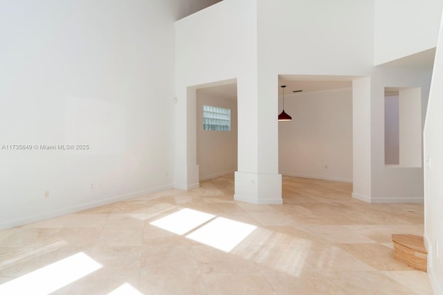 empty room featuring light tile patterned floors and a high ceiling