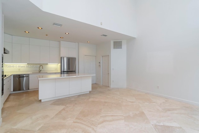 kitchen with white cabinetry, stainless steel appliances, a center island, and sink