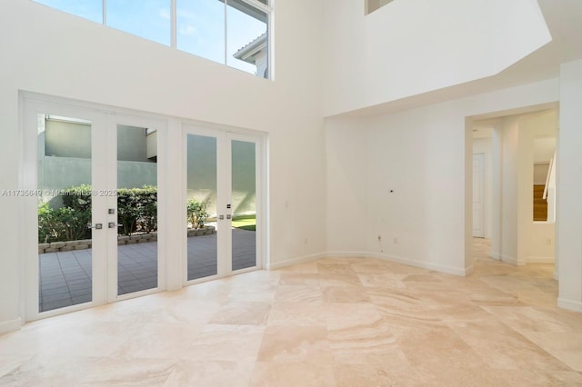 spare room with a towering ceiling and french doors