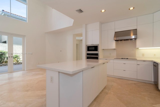 kitchen featuring wall chimney exhaust hood, white cabinetry, a center island, a healthy amount of sunlight, and black appliances