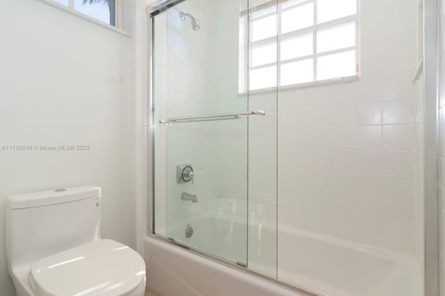 bathroom featuring bath / shower combo with glass door and toilet