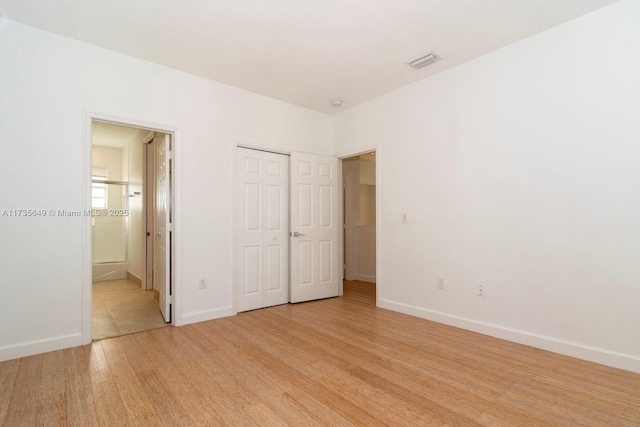 unfurnished bedroom featuring connected bathroom, light hardwood / wood-style floors, and a closet