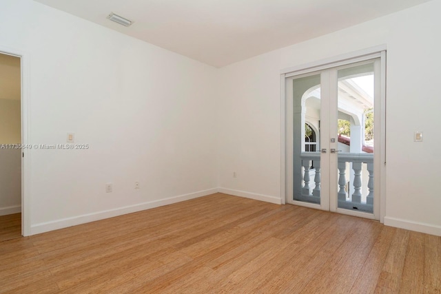 spare room featuring french doors and light wood-type flooring