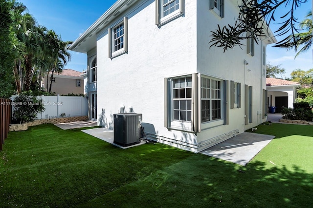 rear view of property with central AC and a lawn