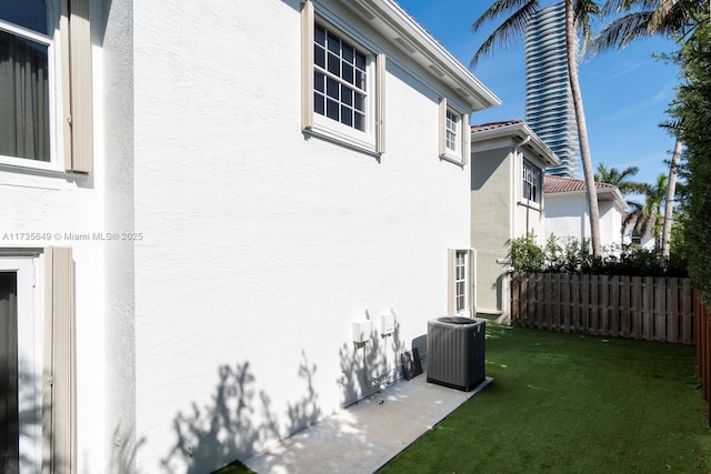 view of side of home featuring central AC unit and a yard