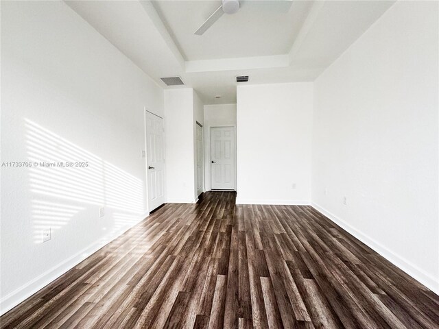 spare room featuring ceiling fan, dark hardwood / wood-style floors, and a raised ceiling