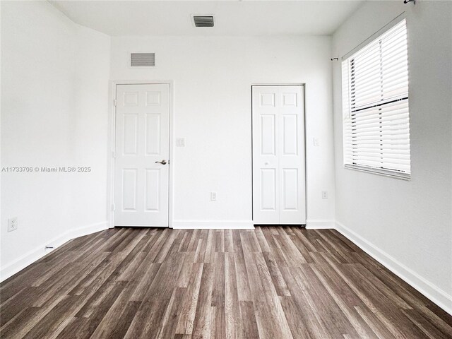 unfurnished bedroom featuring dark wood-type flooring and a closet