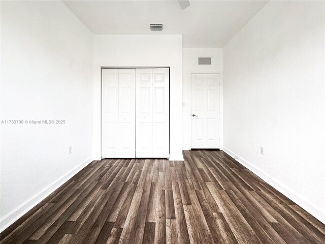 unfurnished bedroom featuring a closet, dark hardwood / wood-style floors, and ceiling fan