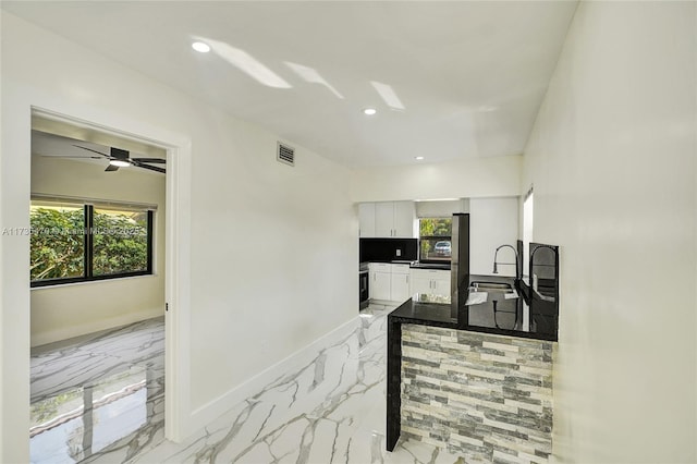 kitchen featuring sink, oven, kitchen peninsula, and white cabinets