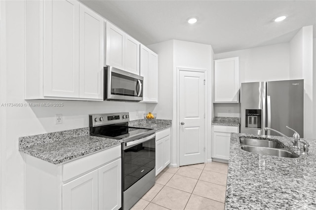 kitchen with sink, stainless steel appliances, light stone counters, white cabinets, and light tile patterned flooring