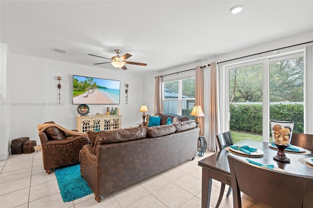 living room featuring ceiling fan, a textured ceiling, and light tile patterned floors