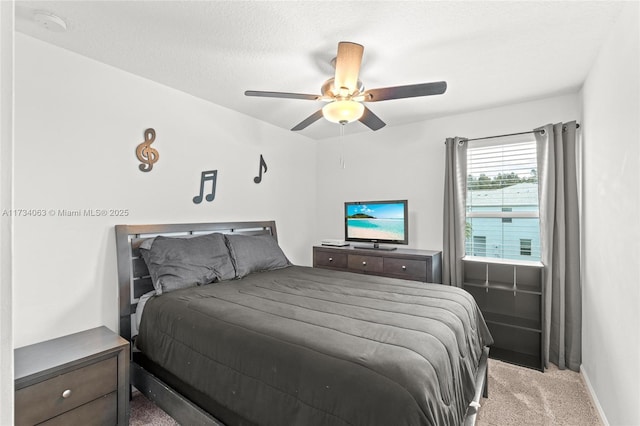 carpeted bedroom featuring ceiling fan and a textured ceiling