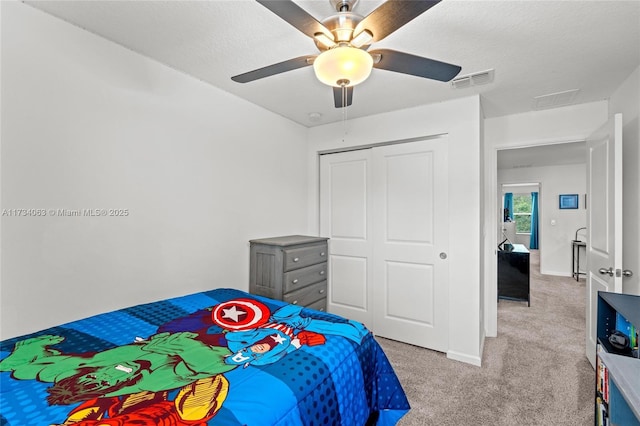 bedroom with ceiling fan, a closet, light carpet, and a textured ceiling