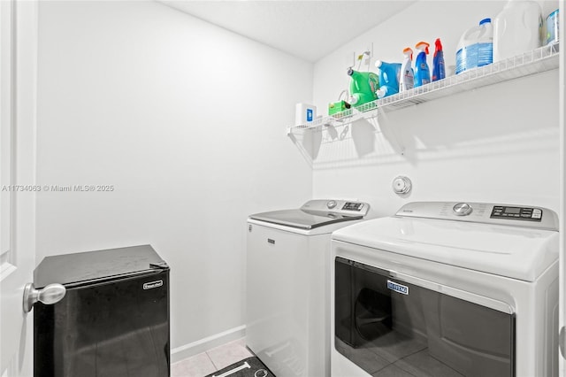 washroom with light tile patterned floors and washing machine and dryer