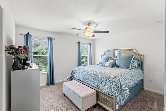 carpeted bedroom featuring ceiling fan, multiple windows, and a textured ceiling