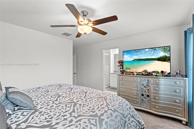 bedroom featuring ceiling fan, light colored carpet, and ensuite bath