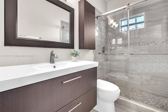 bathroom featuring vanity, toilet, and a shower with door