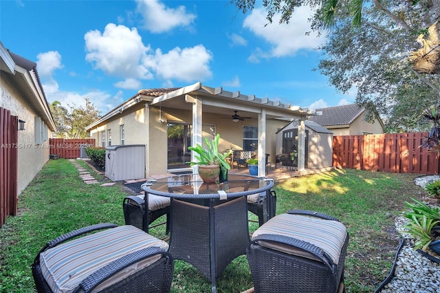 rear view of house with a lawn, ceiling fan, and a storage unit