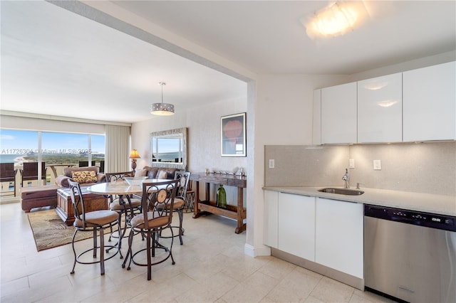 interior space featuring pendant lighting, white cabinetry, dishwasher, sink, and decorative backsplash