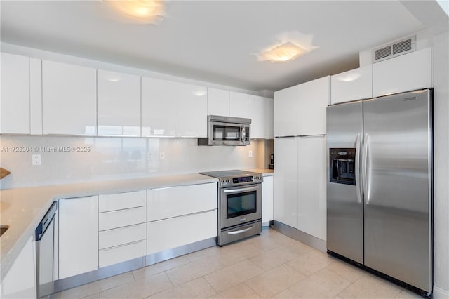 kitchen with stainless steel appliances, white cabinetry, tasteful backsplash, and light tile patterned flooring