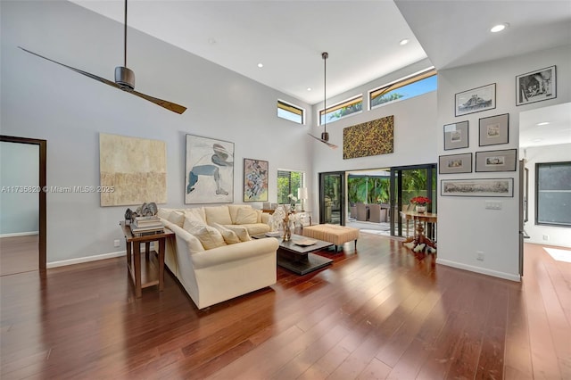 living room featuring ceiling fan, wood-type flooring, and a towering ceiling