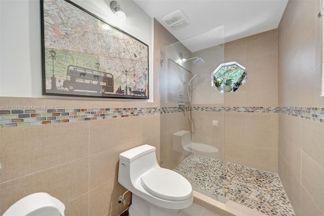 bathroom featuring tile walls, toilet, and a tile shower