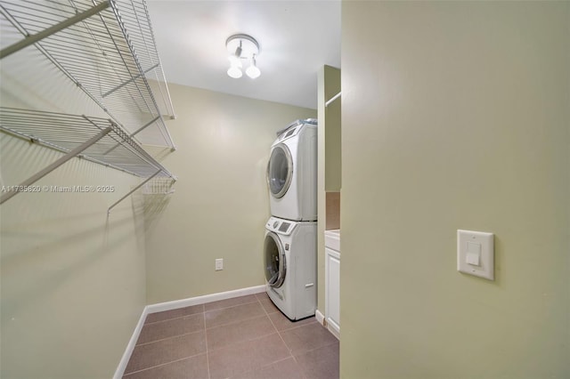 washroom with light tile patterned floors, cabinets, and stacked washing maching and dryer