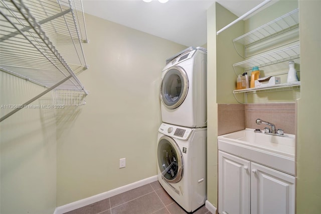 washroom featuring sink, tile patterned floors, cabinets, and stacked washing maching and dryer