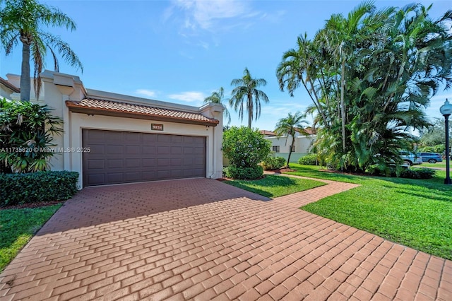 mediterranean / spanish-style house with a garage and a front lawn