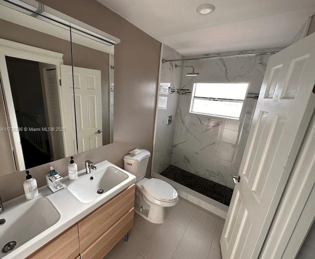 bathroom with vanity, toilet, and a tile shower