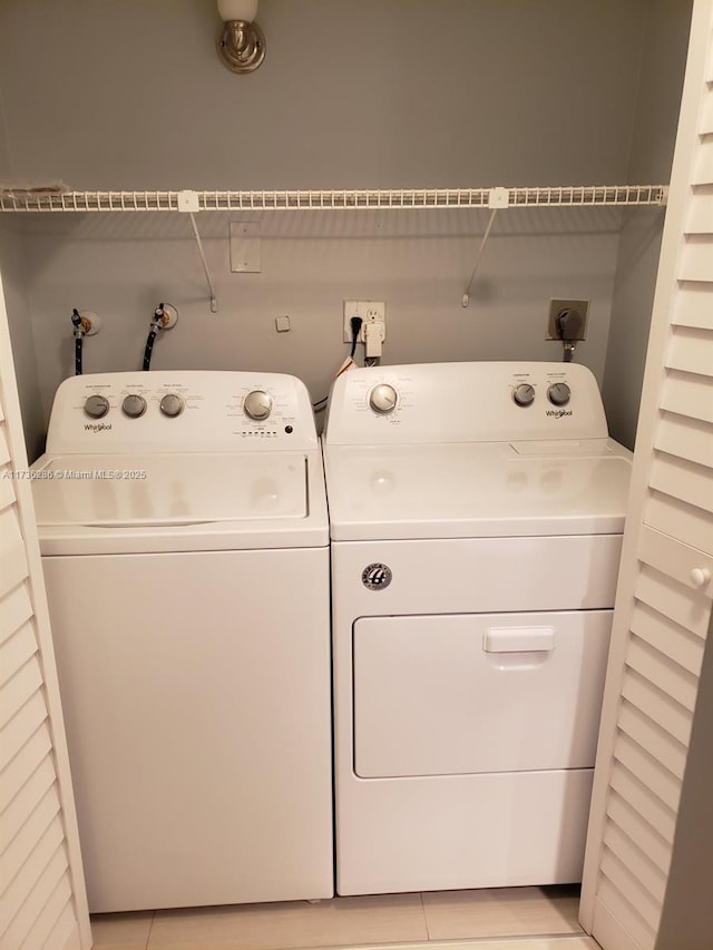 clothes washing area featuring washer and dryer and light tile patterned floors